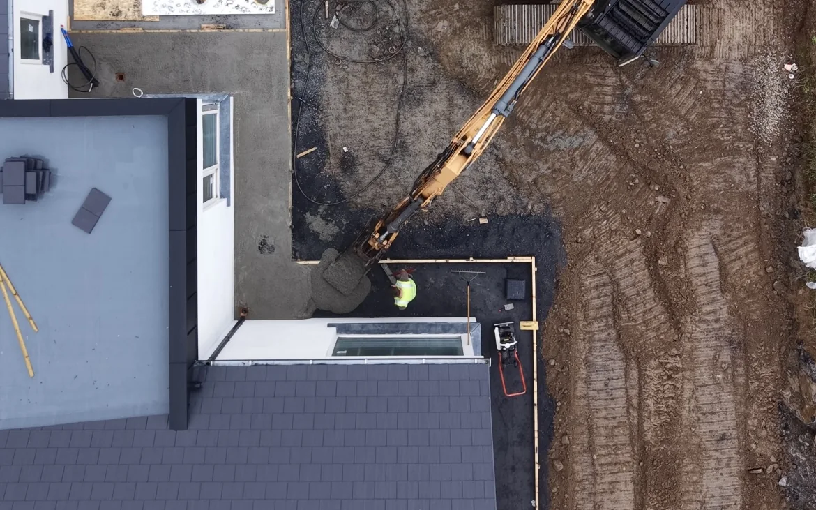 Aerial view of excavator installing a wastewater treatment system beside a rural home